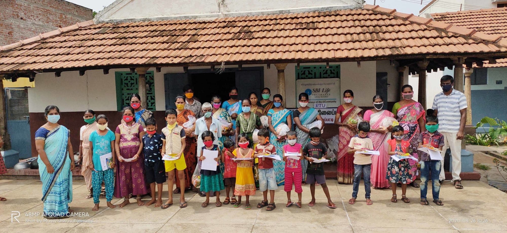 A large group of children with their mothers at school receiving learning materials 