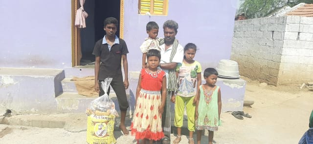 A family receiving their rations outside their home